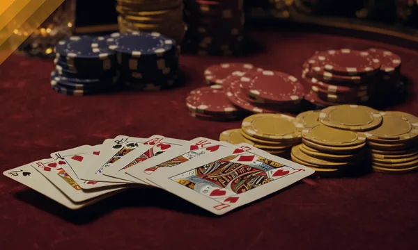 Fanned playing cards, gold coins and chip stacks on red baize for the AE Sexy baccarat rooms