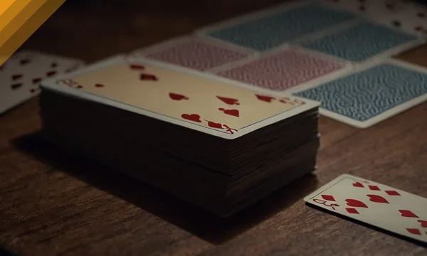 Deck of cards on a wooden table with one card turned for Andar Bahar