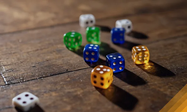 Scattered coloured dice on a wooden board for the Ludo race
